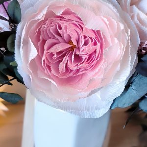 image d'une rose anglaise en papier crépon dans un vase blanc. le cœur de la fleur est rose et les pétales extérieurs blanches